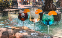A Group Of Glasses With Liquid In Them By A Fountain